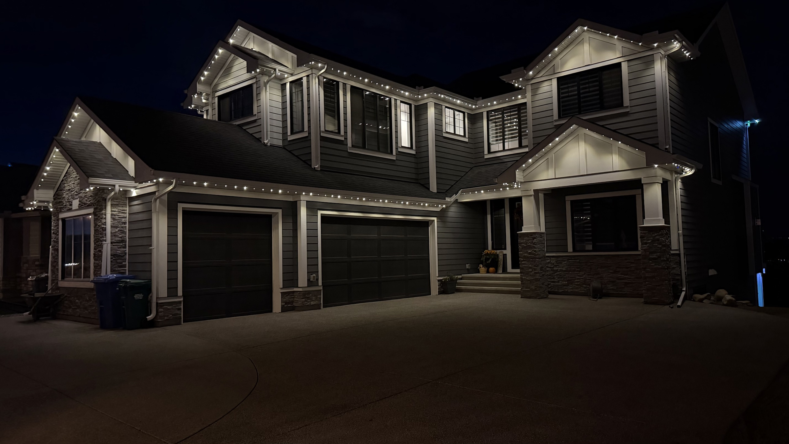 Two-storey Calgary home at night with permanent warm white LED lights running along every eave and gable